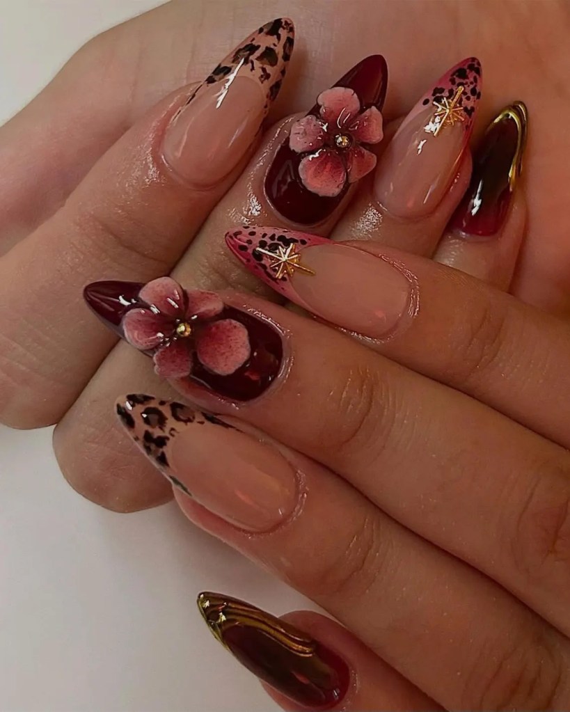 A close-up view of beautifully manicured nails featuring a mix of designs, including leopard print, floral accents, and glossy burgundy finishes.