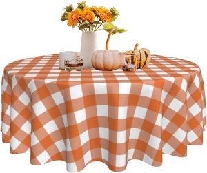 A fall tablescape featuring an orange and white checkered tablecloth, small pumpkins, and a vase of sunflowers.