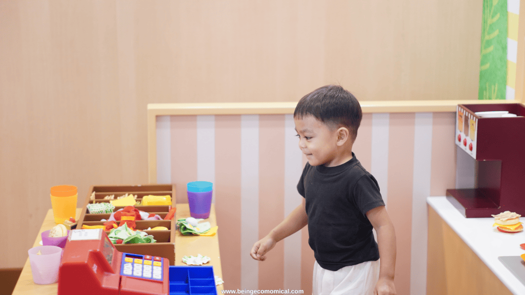 3 year old playing pretend store with a toy cash register and play food