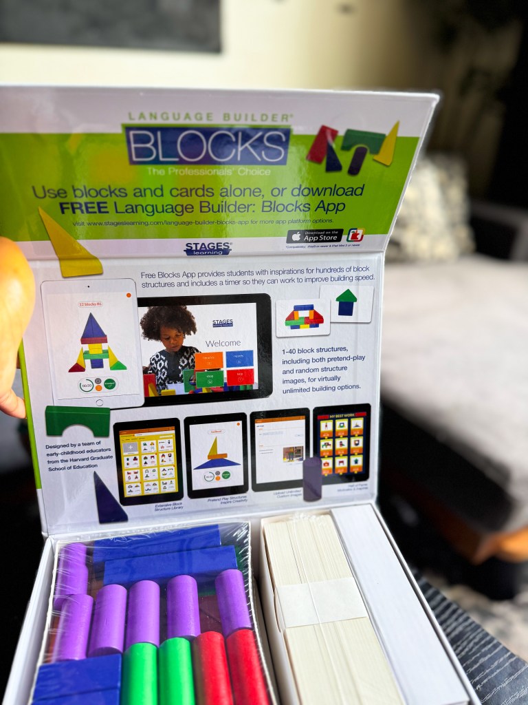An open box of Language Builder Blocks containing colorful building blocks, with instructional materials displayed on the inside lid, promoting the use of the corresponding app for educational purposes.