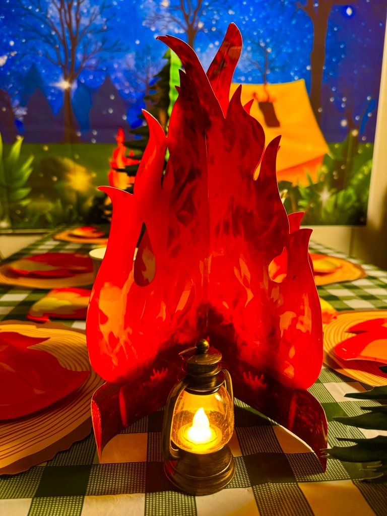Faux campfire centerpiece with glowing lanterns for a camping themed birthday party.