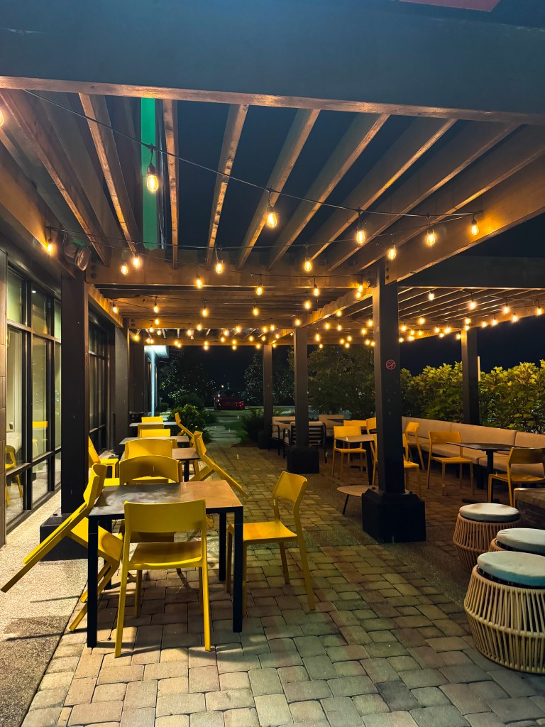 Covered outdoor patio with yellow chairs and string lights at Home2 Suites Pigeon Forge.