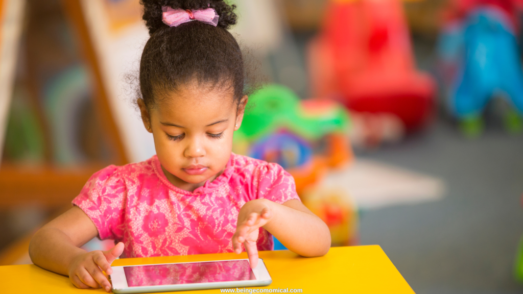 Young child using a tablet at a small table during an educational learning activity.