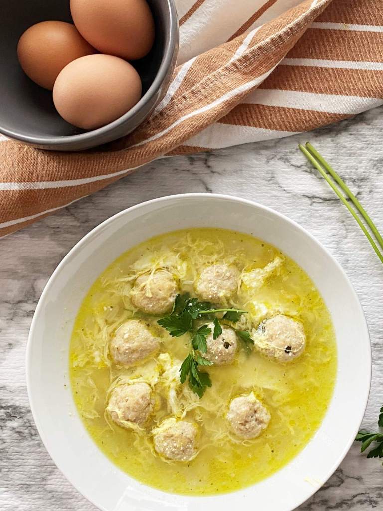 Italian wedding egg drop soup with tender meatballs, leafy greens, and ribbons of egg in a savory broth served in a rustic bowl