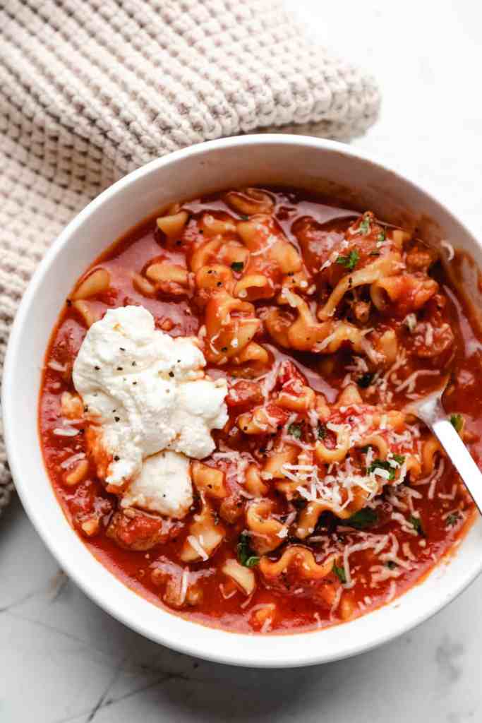 Hearty lasagna soup with ground beef, tomatoes, pasta, and melted cheese served in a rustic bowl