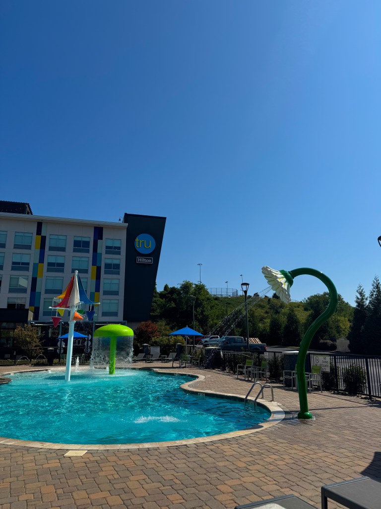 Outdoor pool with splash features and seating at Home2 Suites Pigeon Forge.