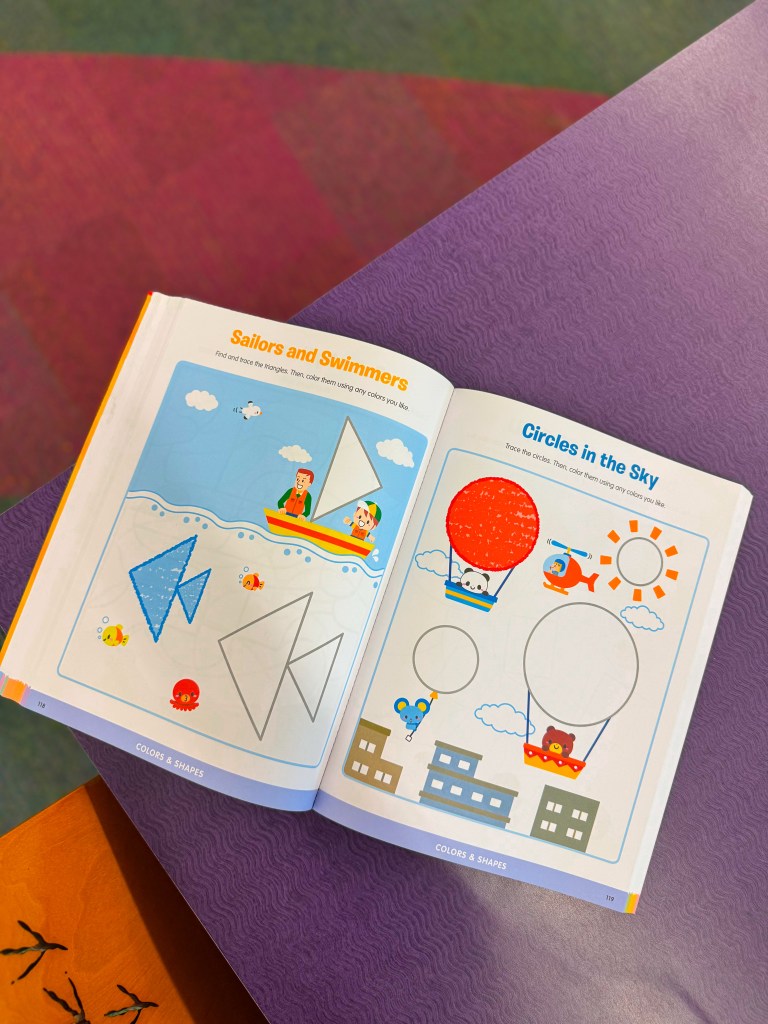 Open coloring book page featuring two activities: 'Sailors and Swimmers' with a boat, sea creatures, and shapes to color on the left, and 'Circles in the Sky' with hot air balloons and buildings on the right.
