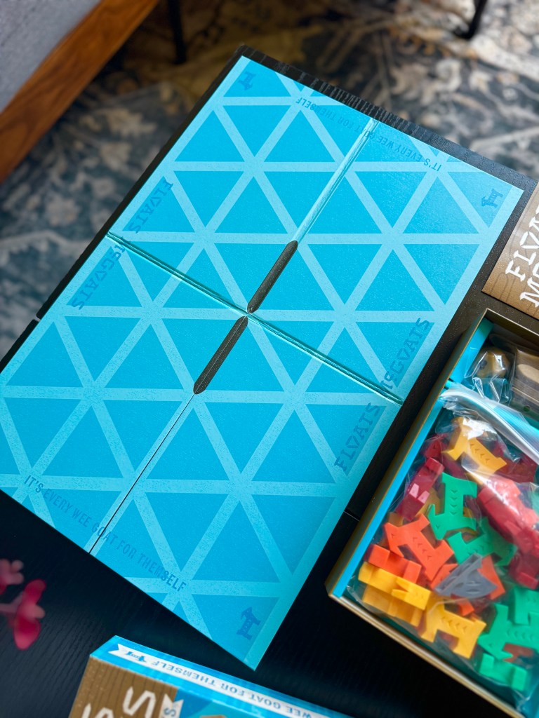 A top-down view of a board game featuring a blue game board with a geometric pattern and surrounding game pieces in various colors.