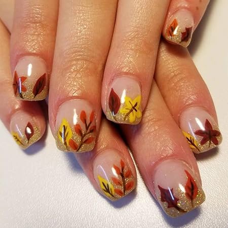 Manicure featuring autumn-themed nail art with colorful leaves in red, yellow, and orange on a nude base with glittery tips.