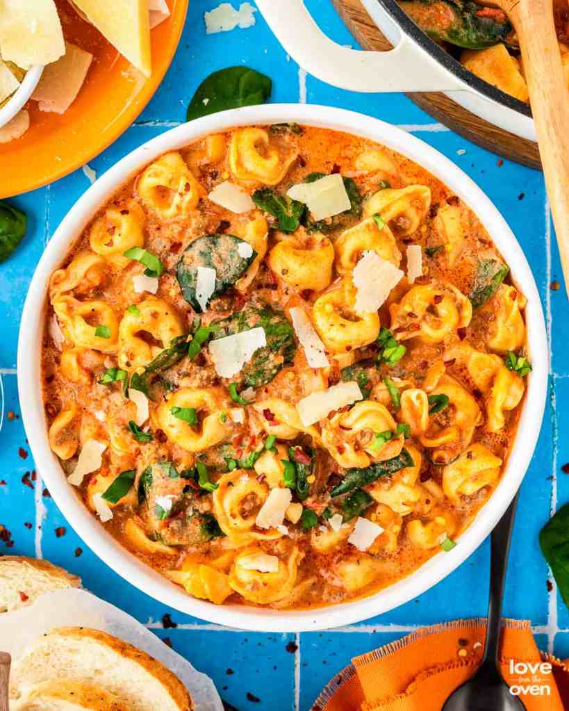 Creamy sausage tortellini soup with Italian sausage, spinach, and cheese tortellini served in a rustic bowl