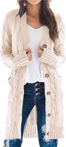 A woman wearing a long, cable-knit cream cardigan over a white t-shirt and distressed denim jeans, showcasing a cozy and stylish fall outfit.