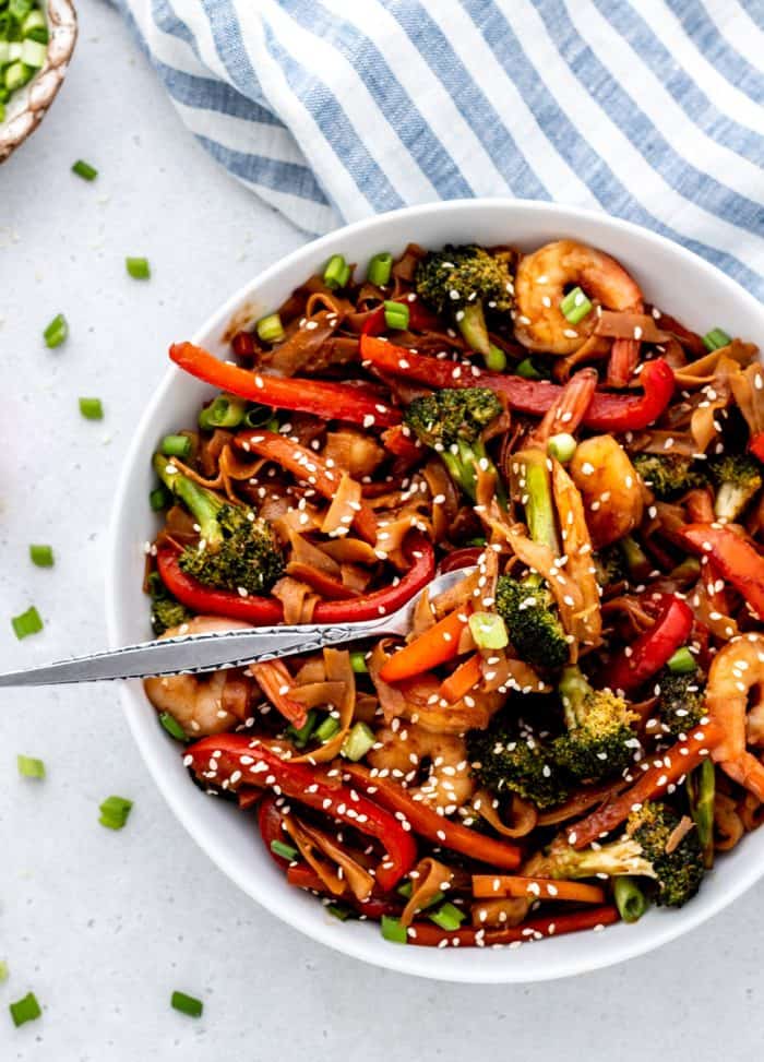 Shrimp noodle stir fry with vegetables and peanut sauce in a skillet