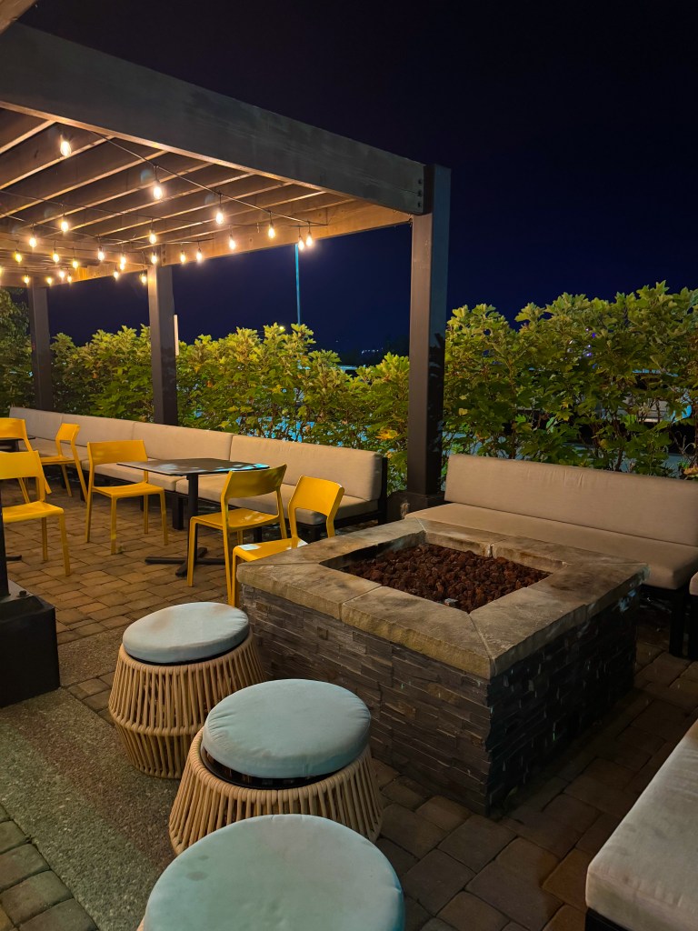 Covered patio seating area with tables and warm string lights at Home2 Suites Pigeon Forge.