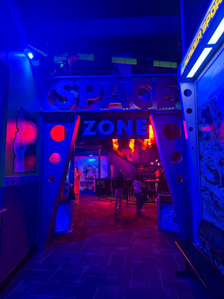 Entrance to a colorful 'Space Zone' arcade area featuring blue and purple lighting.