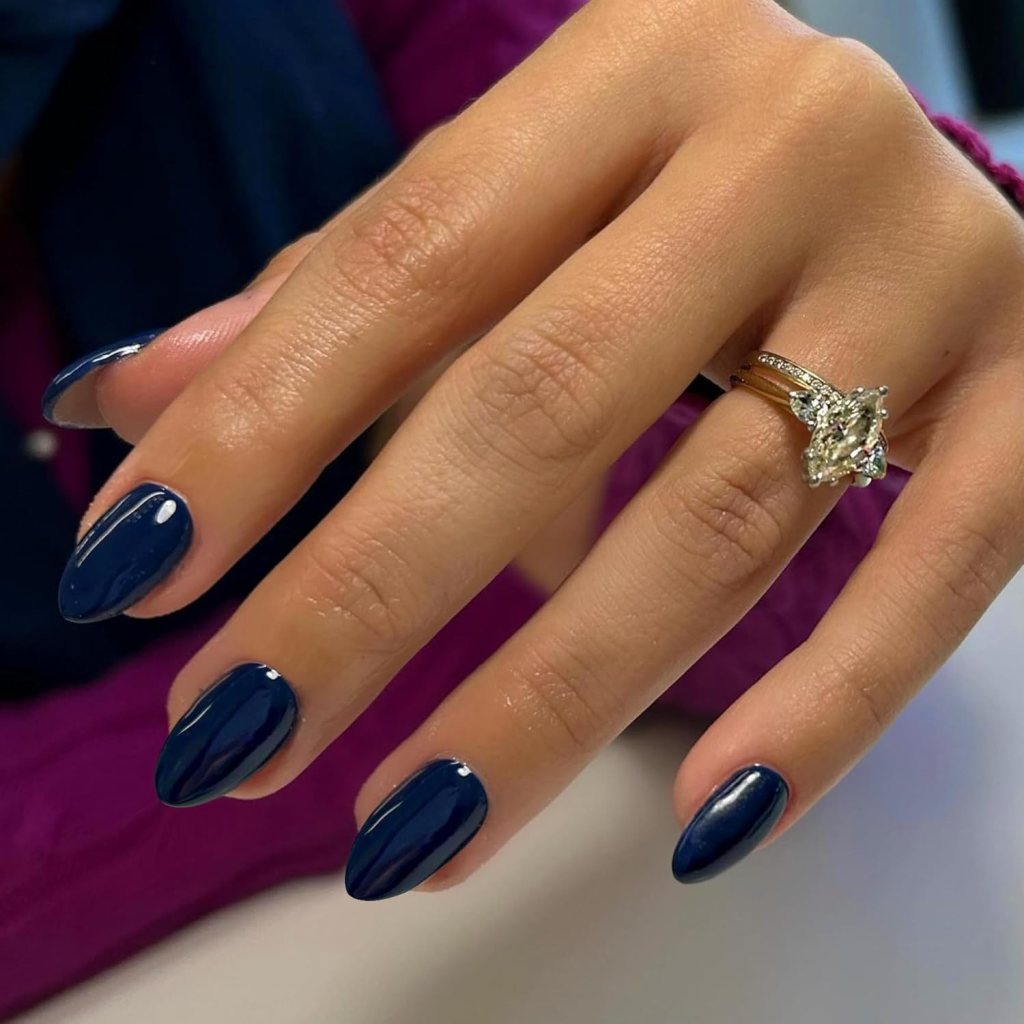 Glossy dark navy blue almond nails with sleek minimalist dark blue polish and elegant almond shape.