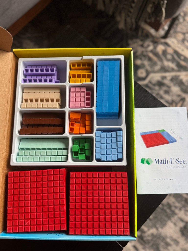 Top view of the Math-U-See Algebra 1 Integer Block Kit, showcasing various colored manipulatives organized in a box with a manual.