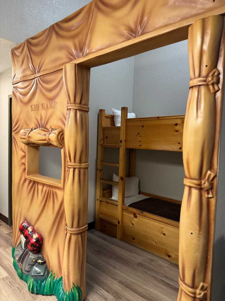 Interior view of a KidKamp Suite at Great Wolf Lodge featuring a carved tent entrance and wooden bunk beds designed for kids.