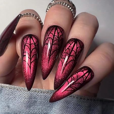 Vibrant ombre stiletto nails featuring black spiderweb designs over a shimmering red base.