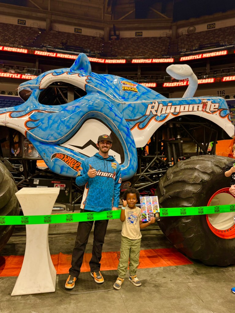Child receives an autograph from the Rhinomite driver beside the monster truck.