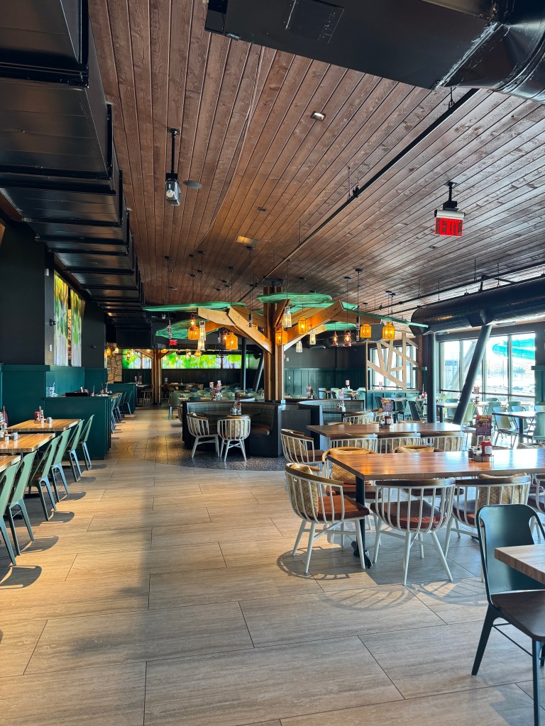 Interior view of a dining area in a restaurant featuring wooden beams, tables, and chairs with a cozy ambiance.