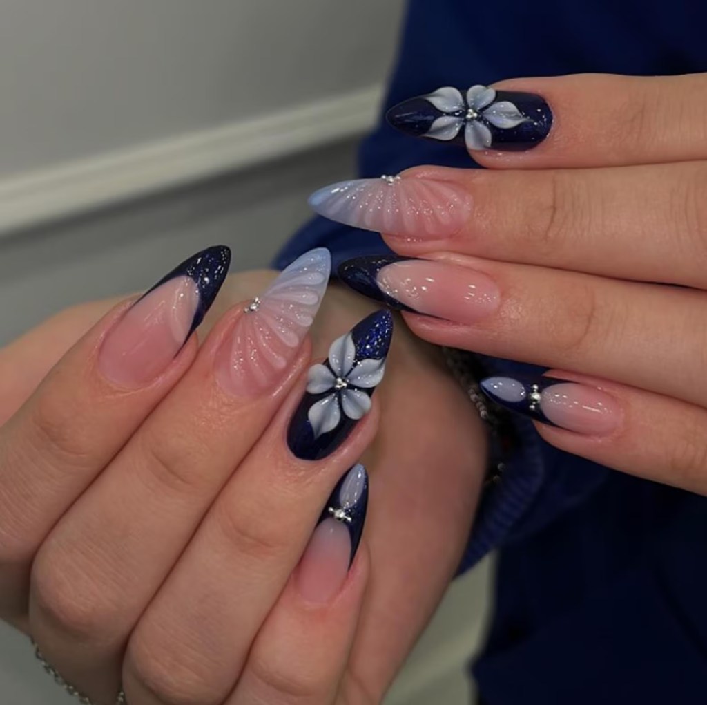 Navy blue floral 3D almond nails with glossy dark blue French tips and raised flower nail art on nude acrylic nails.