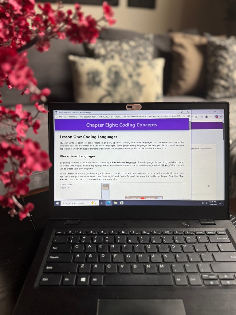 A laptop displaying a lesson on coding concepts from an online tech curriculum, with a close view of the screen content, including examples of block-based coding.