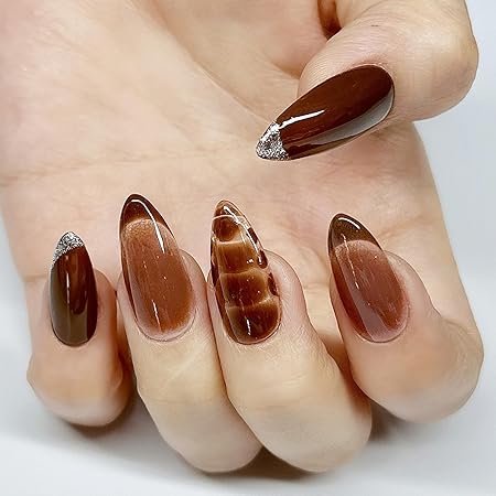Close-up of a hand with beautifully manicured nails featuring a mix of rich brown shades and glossy finishes, including a brown marbled accent nail and silver glitter tips.