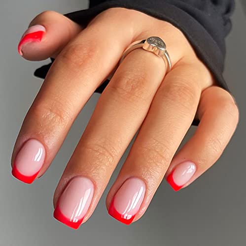 A hand displaying manicured nails with a gradient design, featuring a soft pink base and bold red tips, adorned with a silver ring.