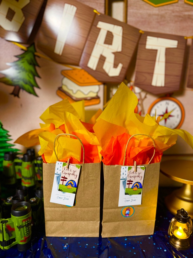 Brown paper camping favor bags with fire-colored tissue paper for a kids birthday party.