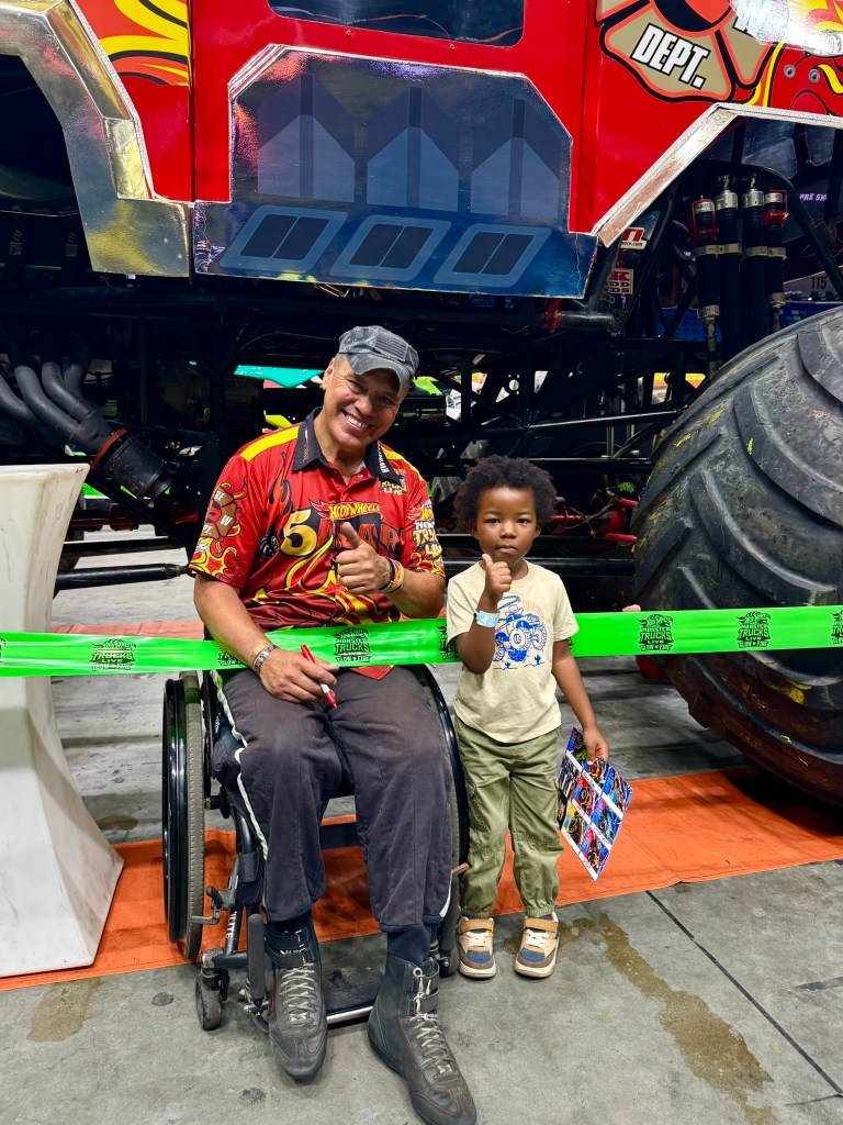 Young child poses with the HW 5-Alarm driver and holds a signed autograph sheet.