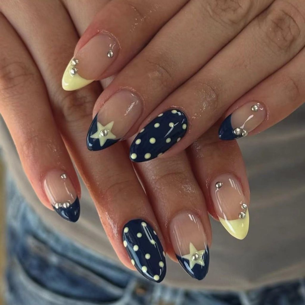 Navy blue and butter yellow French tip nails with star accents, glossy almond-shaped nails, and trendy celestial nail art design.