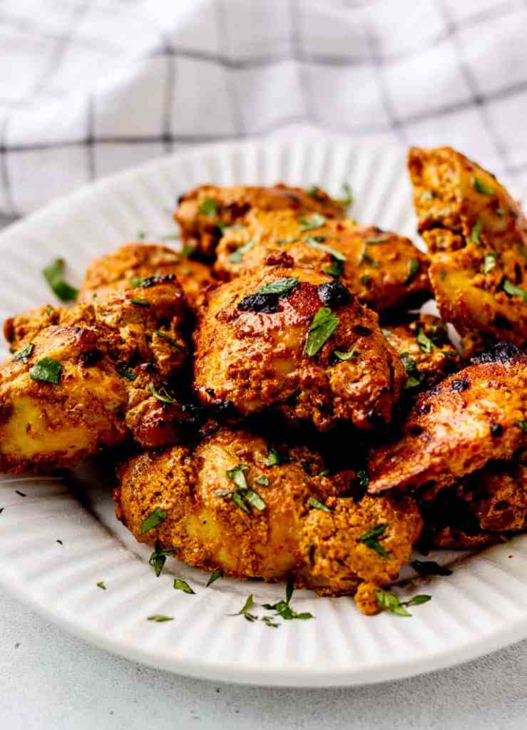 A plate of marinated chicken pieces garnished with fresh herbs, showcasing a golden-brown color and crispy texture, perfect for a flavorful dinner.