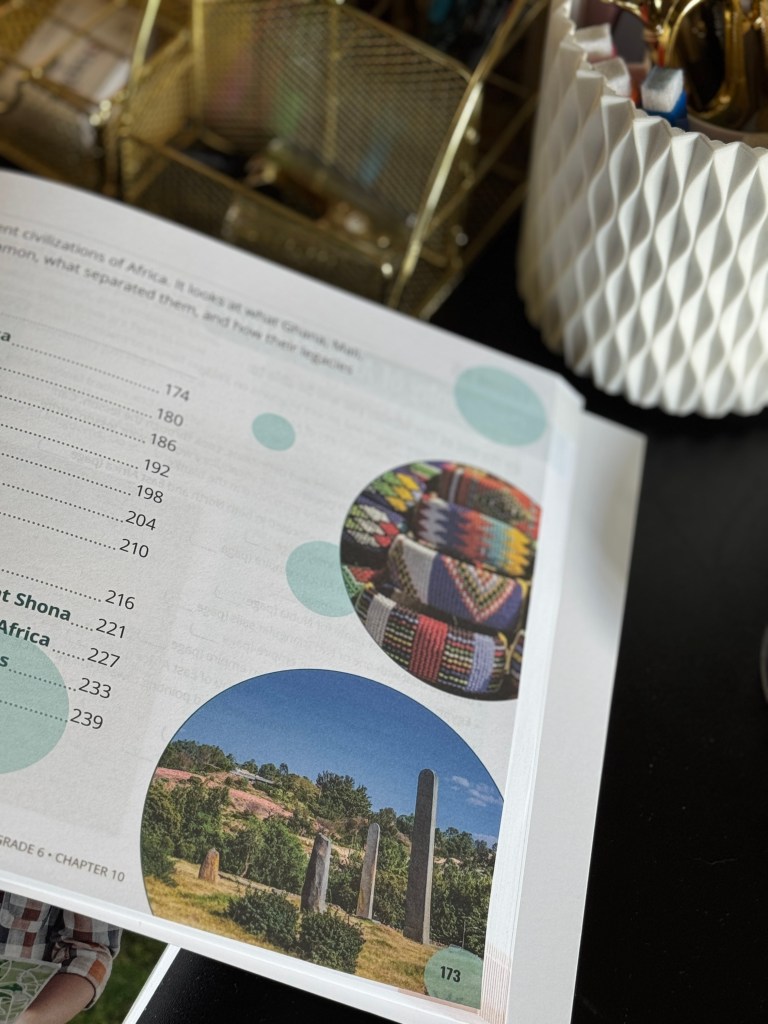 Close-up of a textbook page featuring a table of contents related to African civilizations, with an image of stone structures and colorful patterns in circles.