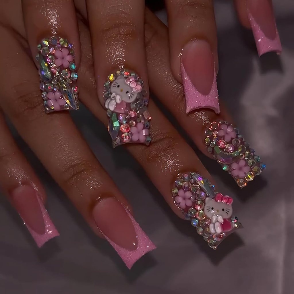 Close-up of intricately designed nails featuring pastel pink and clear acrylics adorned with colorful gems, flowers, and Hello Kitty embellishments.