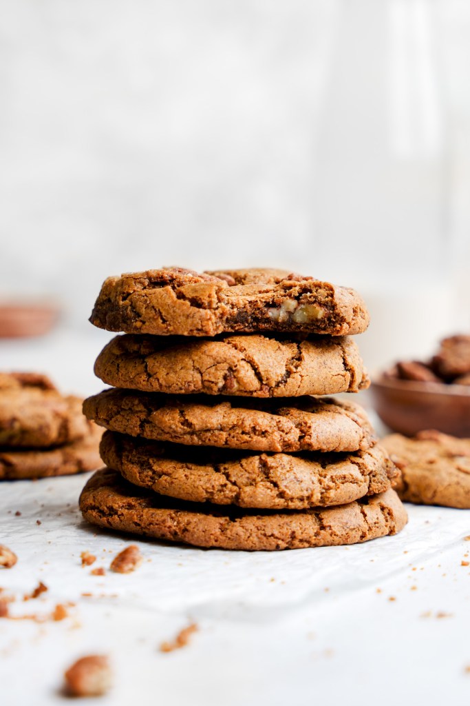 A stack of freshly baked cookies, showcasing a golden-brown color with a slightly cracked surface, set against a blurred background that enhances the cozy, inviting atmosphere of fall baking.