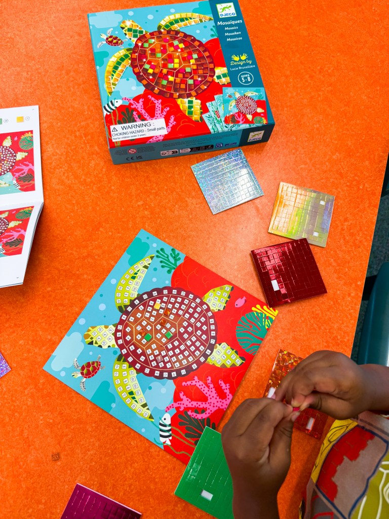 Djeco Caribbean Mosaics turtle activity in progress with metallic sticker sheets spread across the table.