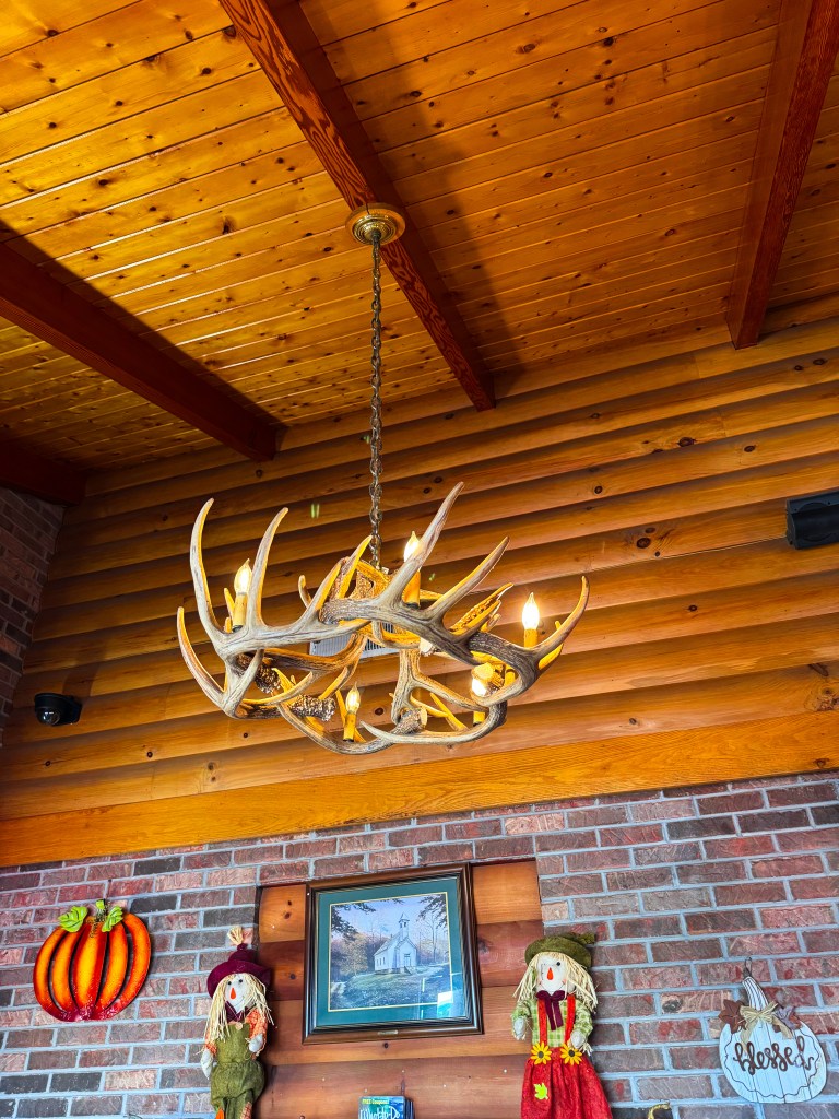 Antler-style chandelier hanging from a wooden ceiling above fall decorations inside Flapjack's Pancake Cabin.