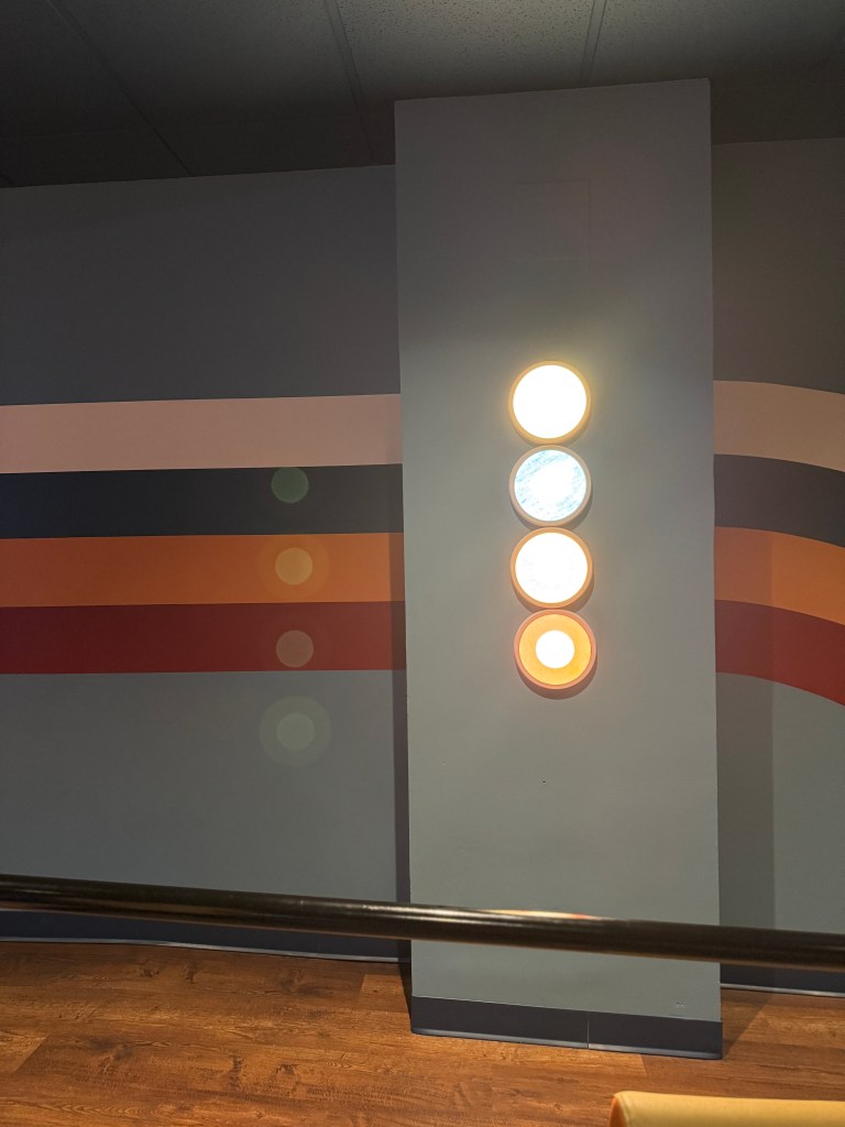 Interior wall with colorful stripes and decorative circular lighting elements in a modern setting.