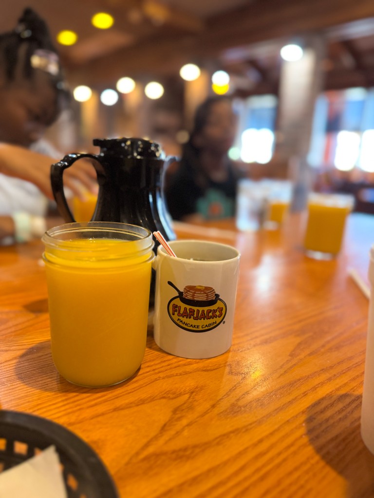 Flapjack's Pancake Cabin branded coffee mug beside a mason jar of orange juice during family breakfast in Pigeon Forge.