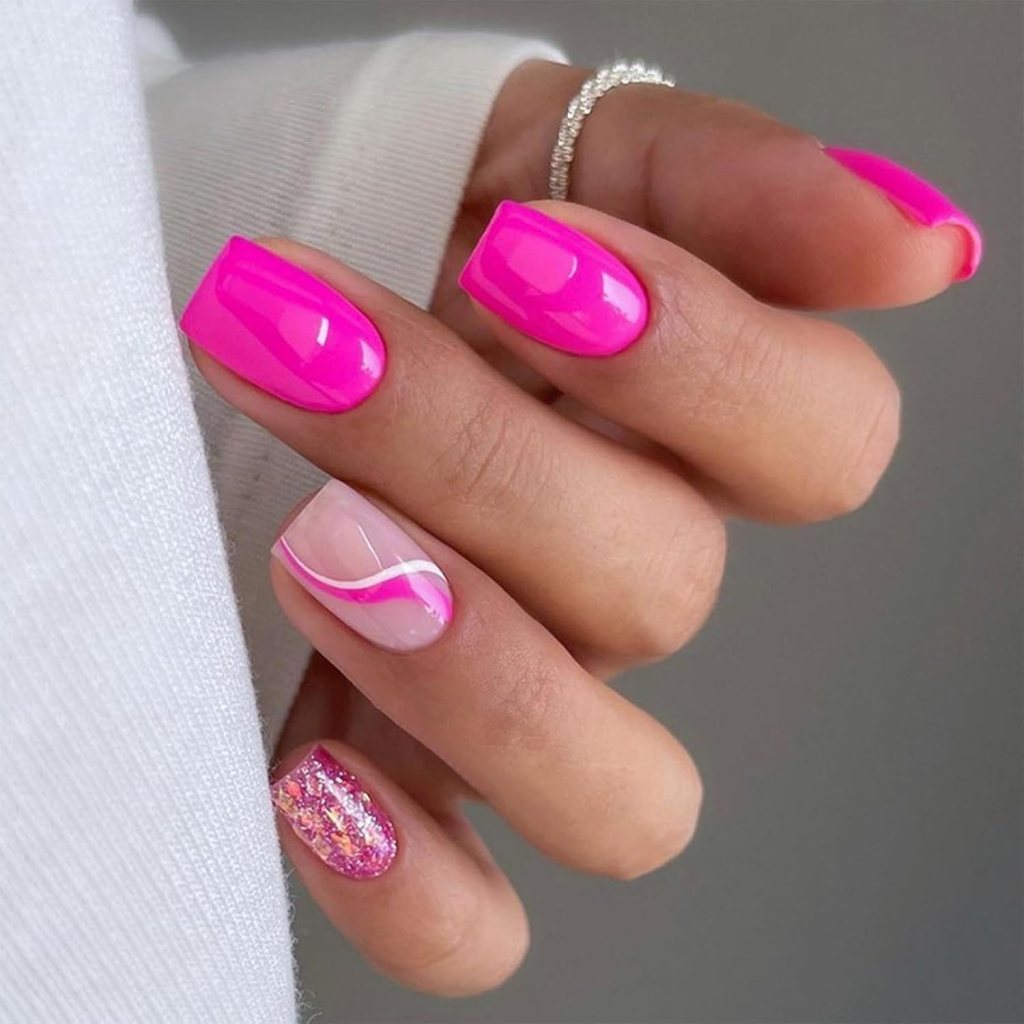 Close-up of a hand with vibrant pink nail polish on most fingers, featuring one nail with a swirl design and another with glitter.