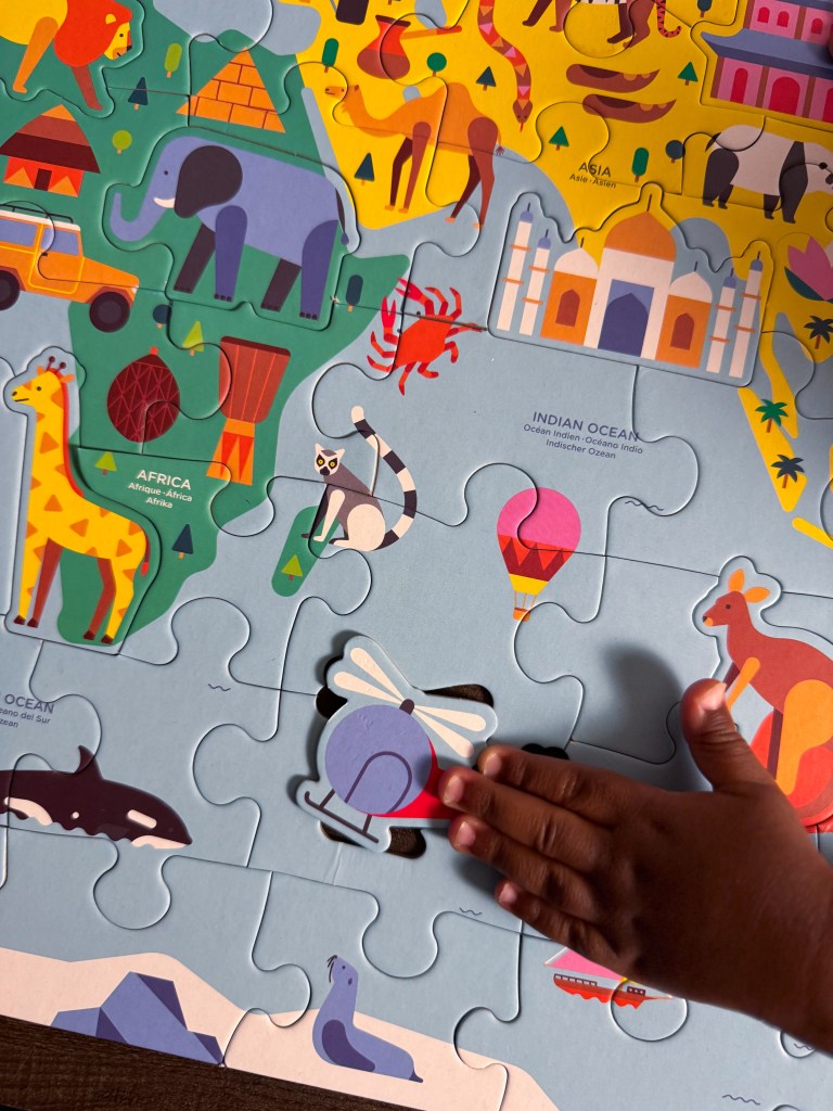 Helicopter landmark piece fitted into the completed world map puzzle near Africa and Asia.