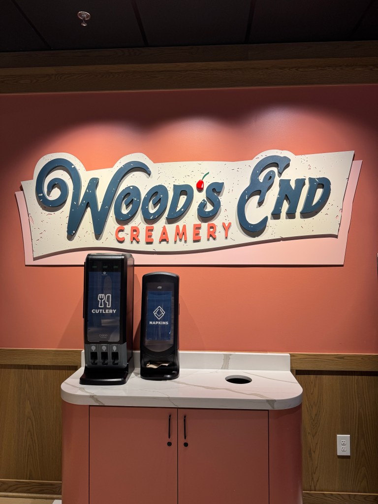 Signage of 'Wood's End Creamery' with cutlery and napkin dispensers in a cozy setting.