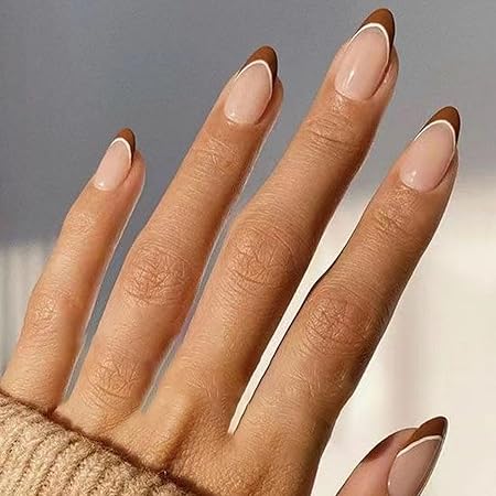 A close-up of a hand showcasing a minimalist mocha French tip manicure, featuring warm brown tips over a soft nude base, with a cozy sweater in the background.