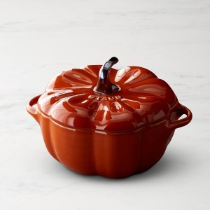 A pumpkin-shaped cocotte in a rich orange hue, perfect for Thanksgiving table decor and serving.