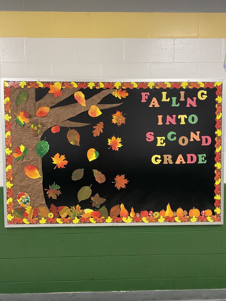 Second grade fall bulletin board with a large paper tree, falling autumn leaves, pumpkins and Falling Into Second Grade lettering.