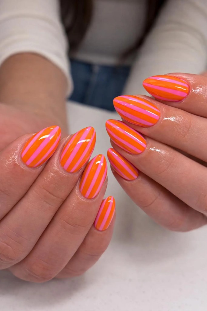 Almond-shaped nails with orange and pink striped summer nail design