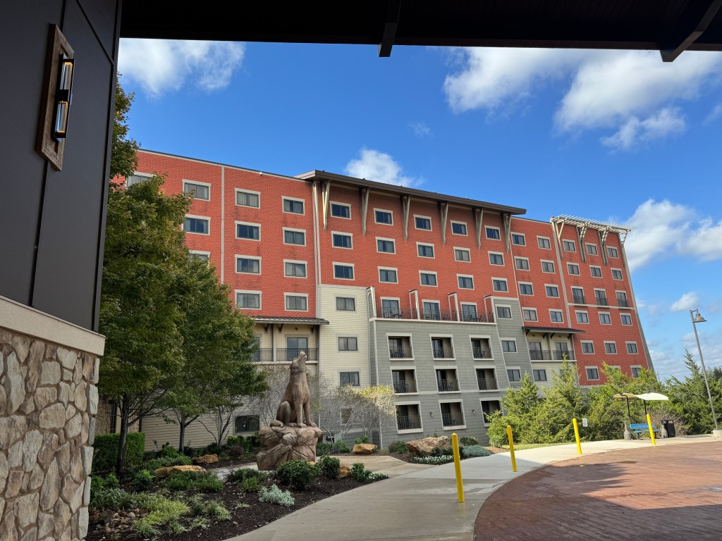 Exterior view of Great Wolf Lodge Grapevine in Texas with a wolf statue and hotel rooms in the background.