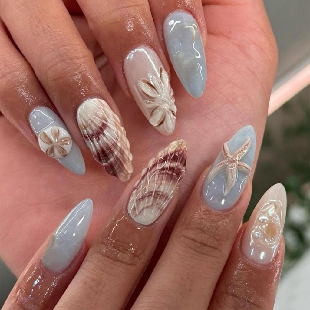 Neutral seashell ocean nails with 3D shell textures, pale blue polish, and classy coastal manicure details
