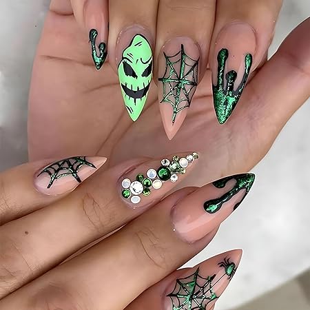 Close-up of Halloween-themed nail art featuring elongated stiletto nails decorated with green accents, spiderweb designs, and a spooky face motif.