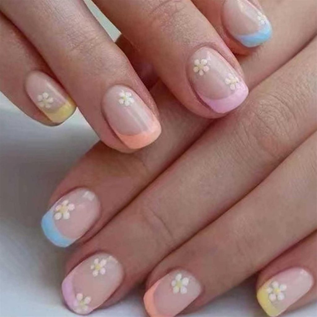 Close-up of hands showing manicured nails with a pastel color scheme and small flower designs on each nail.